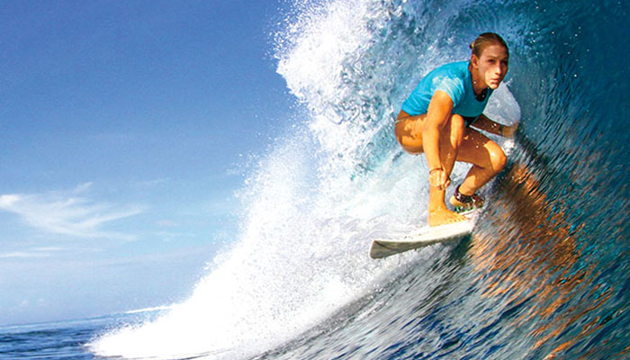 A surfer crouched on a board, riding a wave