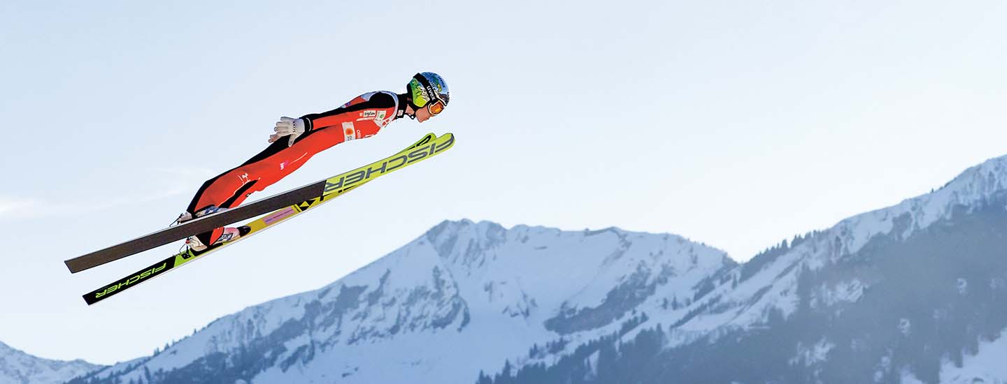 Person skiing high in the air against a mountain backdrop